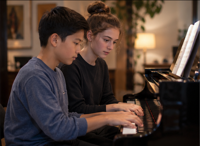 Two middle school students playing a duet at the piano